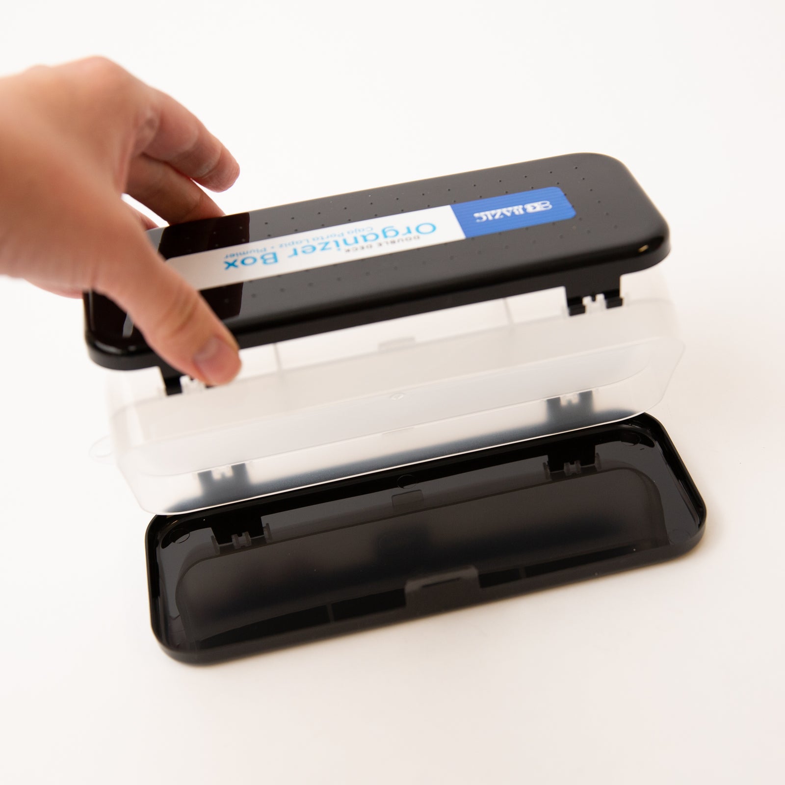 Hand opening a black organizer box with a clear lid on a white background