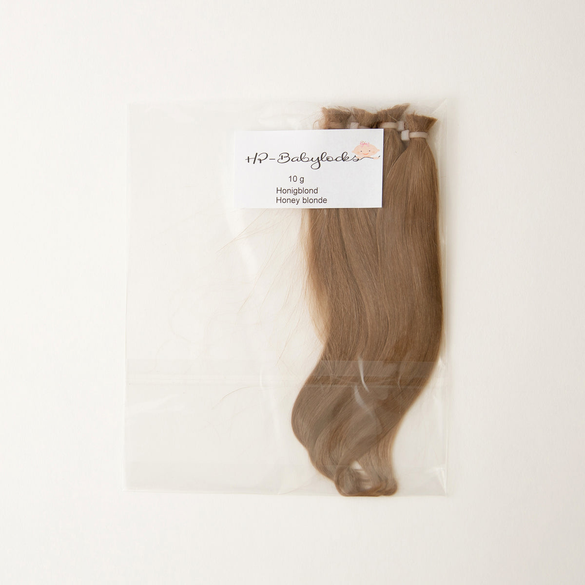 A 10g bundle of hair extensions in Honey Blonde, packaged in a clear plastic bag with a white label, shown against a plain white background.