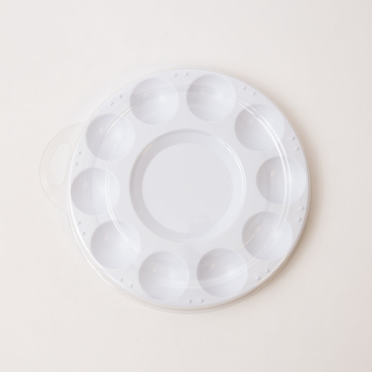 White plastic mixing paint palette tray with multiple compartments on a light beige background